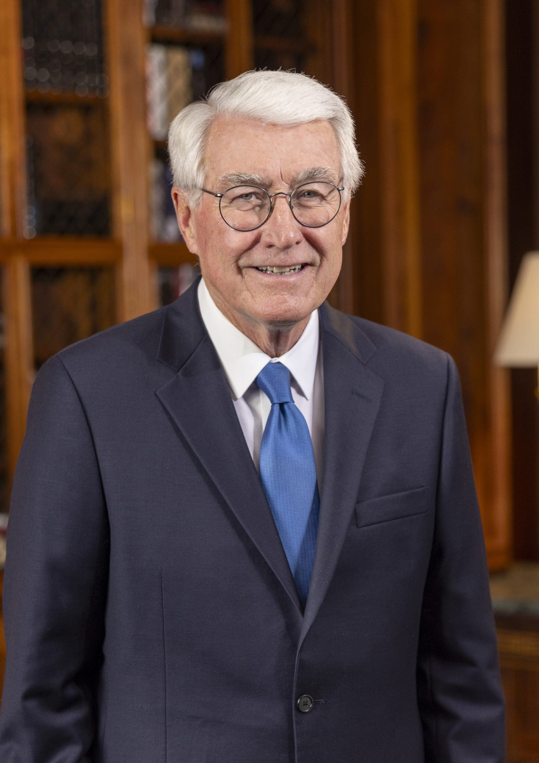 Jim Edgar stands in a black suit with a blue tie in his office