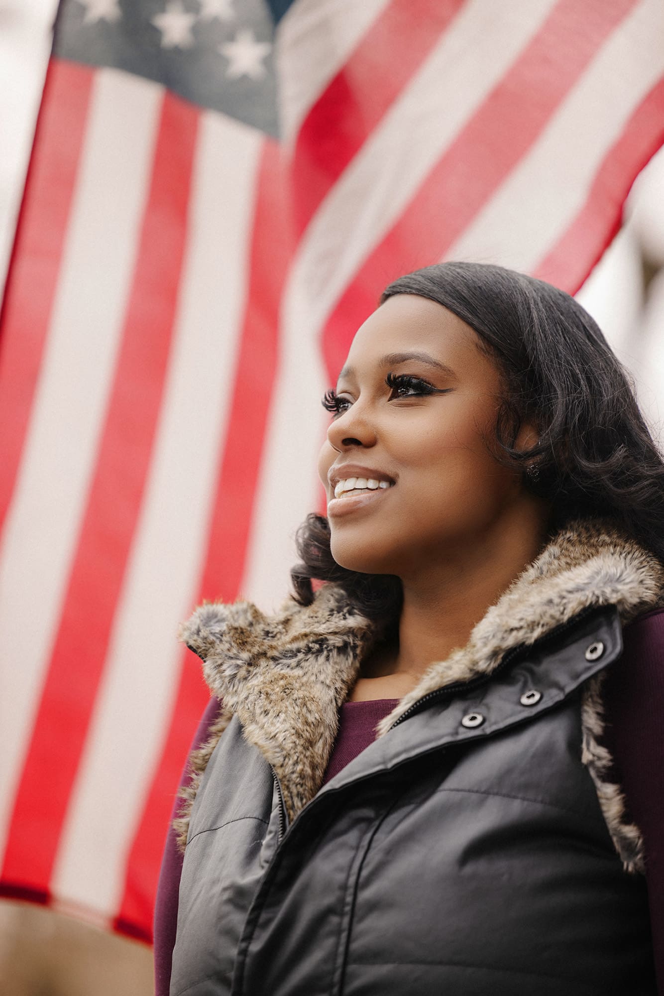 Shantel Franklin, a black woman with shoulder-length hair, stands in front of an American flag and smiles confidently
